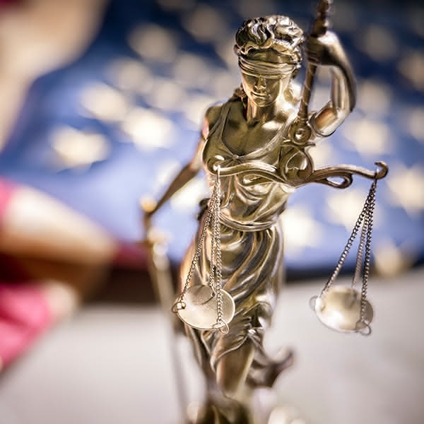 A cast figure of Lady Justice wearing a blindfold, holding up a pair of scales.